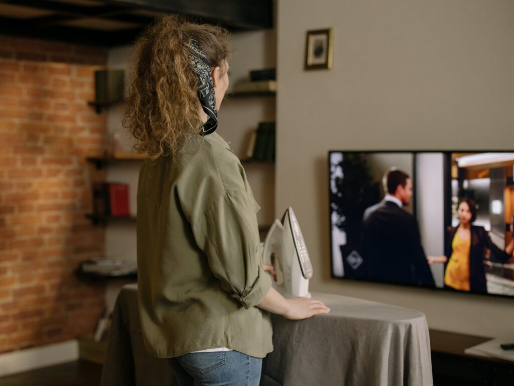 A Woman Watching TV While Ironing