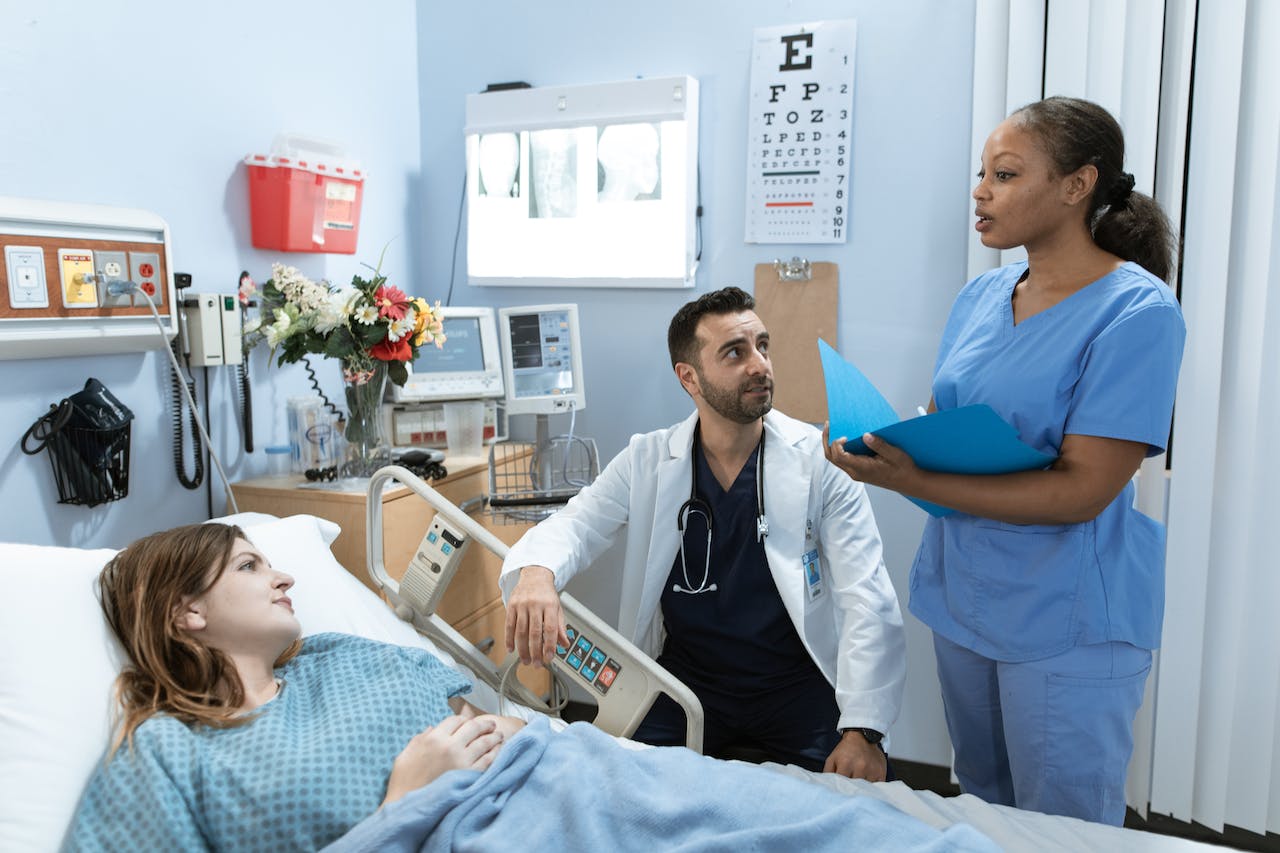 two healthcare workers meeting with a deaf patient in her hospital bed